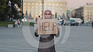 Muslim sad upset worried woman wearing hijab islamic frightened poor girl standing in city on street holding cardboard