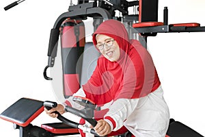 Muslim senior woman riding exercise bike