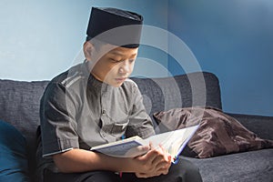 Muslim student reading the Quran wearing a skullcap with solemnly