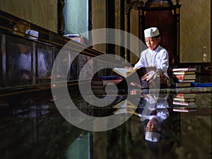 Muslim student studying and reading Islam holy quran book in mosque