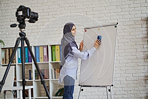 Muslim teacher cleaning the whiteboard while making a video