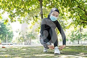 muslim woman athlete with face mask tying her shoes