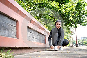 muslim woman athlete tying her shoes before running outdoor