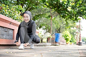 muslim woman athlete tying her shoes before running outdoor
