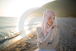 Muslim woman on the beach spiritual portrait. Humble muslim woman praying on the beach. Summer holiday, muslim woman walking