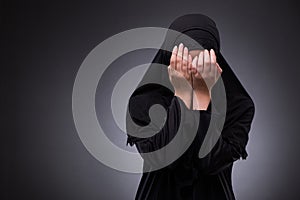 The muslim woman in black dress against dark background