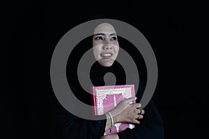 Muslim woman in black Muslim veil hijab holding the Qur\'an and smile