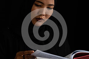 Muslim woman in black Muslim veil hijab reading the Qur'an