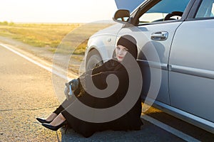 Muslim woman breaking car on the road
