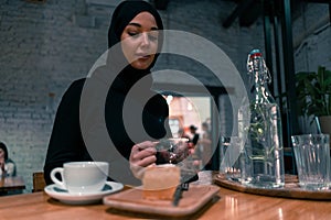 Muslim woman in cafe. Concept of living full life in contemporary tolerable society. Active lifestyle of muslim woman