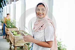Muslim woman, cellphone and happy in greenhouse for plant research, ecology and social media posts. Female botanist