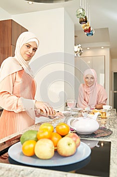 Muslim woman cooking food with friend in kitchen