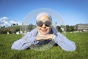 Muslim woman cutely folded her arms and poses on the green grass