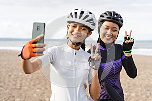 muslim woman cyclist taking selfie photo together at the beach