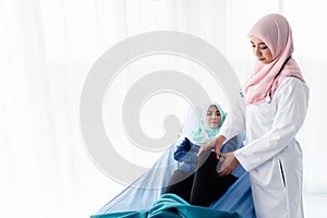 Muslim woman doctor examining the knees patients