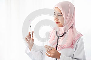 Muslim woman doctor holding a syringe