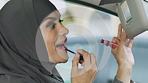 Muslim woman doing makeup in car while stuck in traffic jam, risk of accident