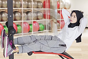 Muslim woman doing sit up at gym