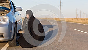 Muslim woman driver changes car wheel