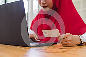 Muslim woman hands holding credit card and using laptop for online shopping.
