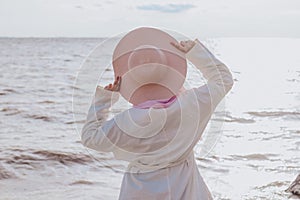 Muslim woman in a hat in a white shirt on the shore.