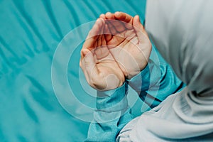 Muslim woman in a headscarf praying makes a dua.