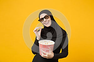 Muslim woman in hijab black clothes 3d imax glasses watch movie film hold bucket popcorn, eat pop corn isolated on