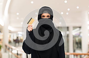 Muslim woman in hijab with credit card over white
