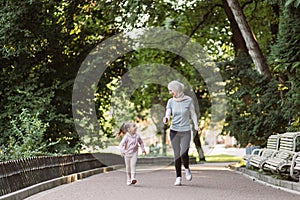 Muslim woman in hijab enjoying jogging together in park with her cute active little daughter