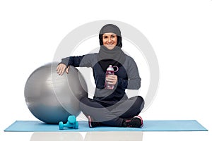 Muslim woman in hijab with fitness ball and bottle