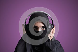 Muslim woman in hijab listening to music with wireless headset