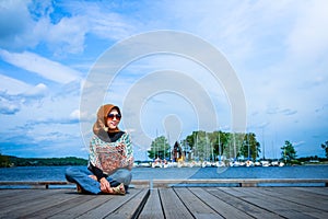 A muslim woman with hijab pose on a wooden dock