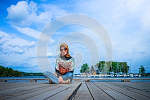 A muslim woman with hijab pose on a wooden dock