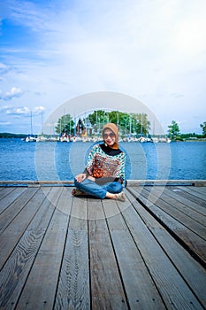 A muslim woman with hijab pose on a wooden dock