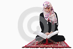 Muslim woman in hijab reading quaran holy book