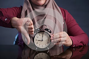 Muslim Woman Holding Clock Pointing at Nine O& x27;Clock, Lateness Concept photo