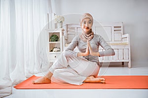 muslim woman instructor wearing hijab yoga pilates half fish pose mattress