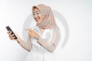 muslim woman laugh with finger pointing on her mobile phone