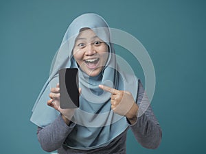 Muslim Woman Looking at Camera Smiling and Shows Smart Phone, Phone Mock Up