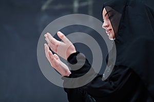 Muslim woman making traditional prayer to God in front of black chalkboard