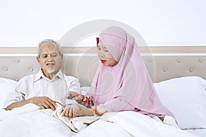 Muslim woman measuring her husband blood pressure