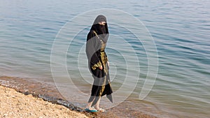 A Muslim woman in national clothes wets her feet