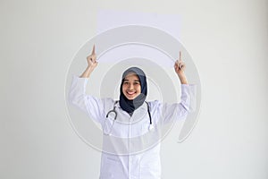 Muslim woman nurse smile isolated white background holding an empty white placard for insert a concept for advertisement,..