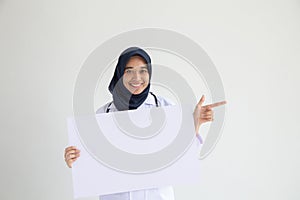 Muslim woman nurse smile isolated white background holding an empty white placard for insert a concept for advertisement,.