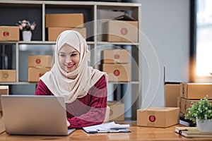 Muslim Woman online store small business owner seller entrepreneur packing package post shipping box preparing delivery