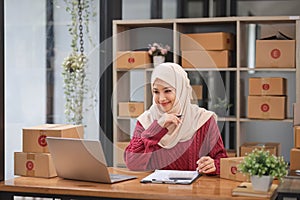 Muslim Woman online store small business owner seller entrepreneur packing package post shipping box preparing delivery