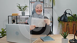 Muslim woman open envelope letter feel happy, career growth advance promotion, bank loan approve