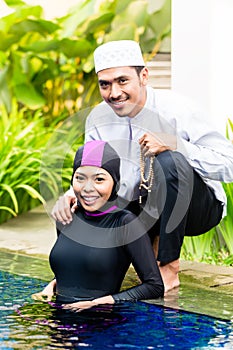 Mujer musulmana en piscina un saludo su marido 