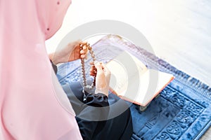 Muslim woman pray with beads and read quran