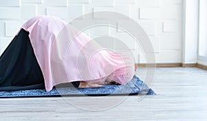 Muslim woman pray on hijab praying on mat indoors